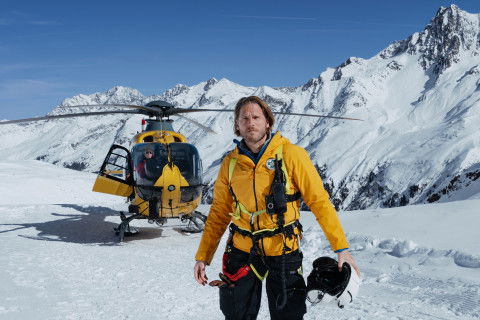 Markus Kofler (Sebastian Ströbel) steht vor einem Helikopter.