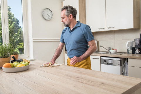 Ein Mann putzt seine Küche.